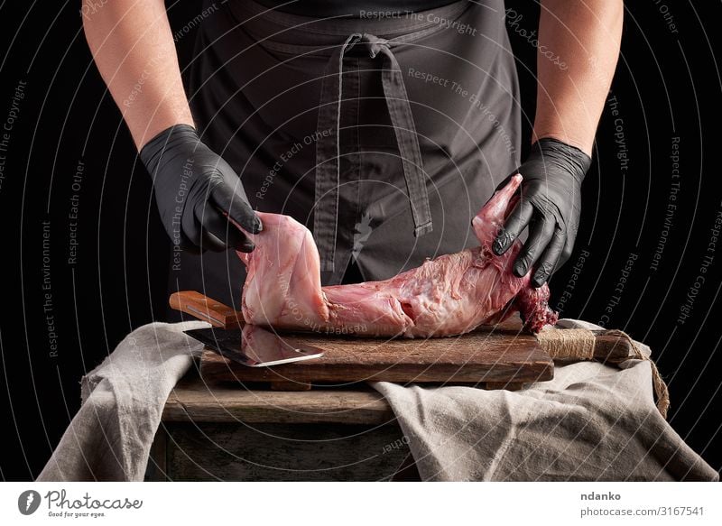 chef in black latex gloves holds a whole rabbit carcass Meat Nutrition Dinner Knives Table Kitchen Man Adults Hand Gloves Wood Eating Make Dark Fresh Red Black