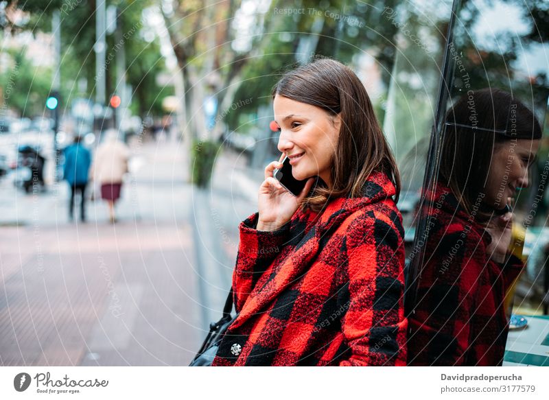 pretty young woman standing on glass on the street using smartphone cell technology smile daylight looking away device gadget conversation outdoors city tail