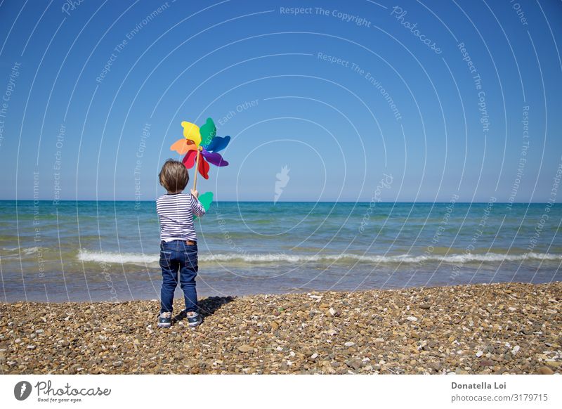 Child from behind holds a colorful pinwheel in front of the sea Joy Summer Beach Ocean Human being Masculine Boy (child) Infancy Body 1 3 - 8 years Environment