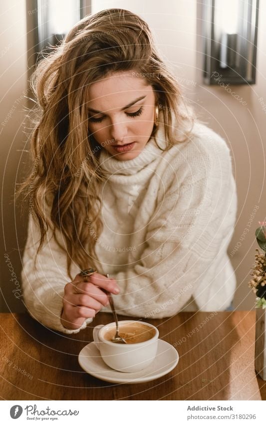 Elegant woman mixing coffee in cafe Woman Café Coffee Stir To enjoy Sit Table Youth (Young adults) Lifestyle Leisure and hobbies Rest Relaxation Drinking Cup