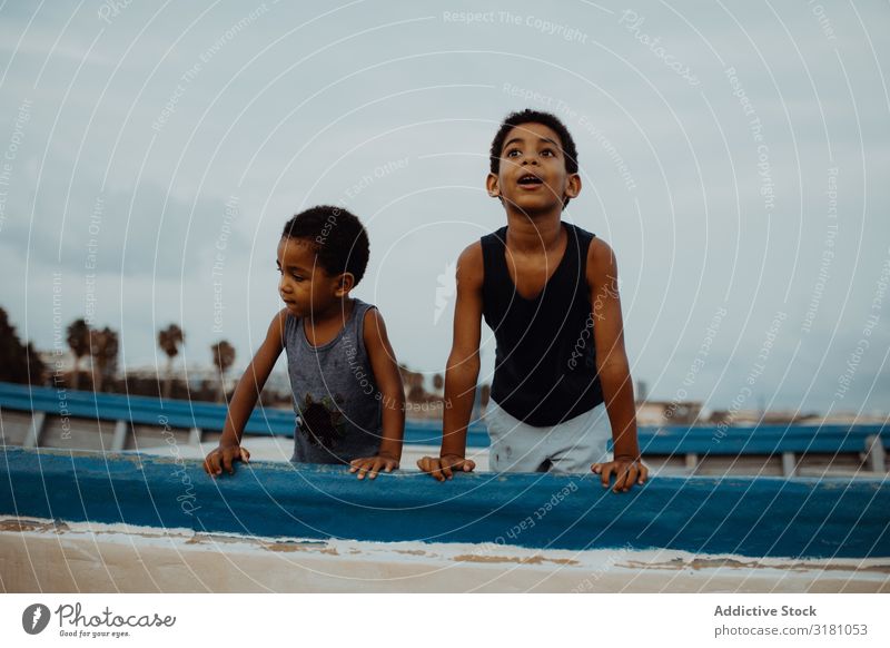 Amazed black boys on boat Boy (child) Watercraft Beach Clouds Sky Black Together Joy Lean Vessel Child siblings brothers African-American Leisure and hobbies