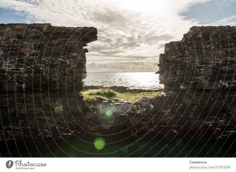 The breakthrough in the wall of a ruin gives a view to the sea Nature Landscape Elements Sky Clouds Winter Beautiful weather Grass Waves coast Ocean Ruin