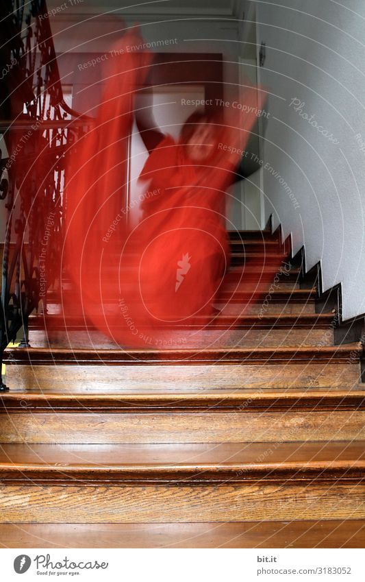 Man waving orange cloth on an old wooden staircase. Surrealistic adult waves with cloth at home in nostalgic staircase. Blurred, disguised, blurred sleepwalker, ghost, ghost with cloth in motion blur.