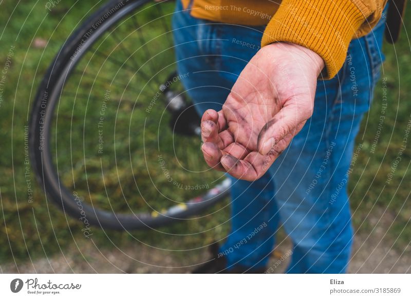 A man has dirty hands after fixing his bike Cycling Dirty Repair Bicycle tyre by hand oil bicycle repair Man Flat tire Litterbug Colour photo Exterior shot Day