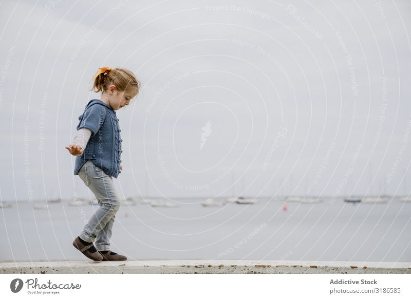 Girl balancing on border near sea Border Balance Walking Ocean Coast outstretched arms Small Lifestyle Leisure and hobbies Child Easygoing Water Beach Dull