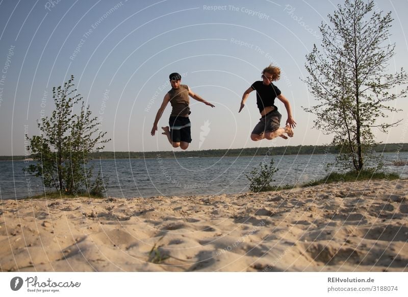 2 men jump into the air at a lake Day Jump Movement Adults 18 - 30 years Youth (Young adults) Human being Joy Exterior shot Colour photo Full-length