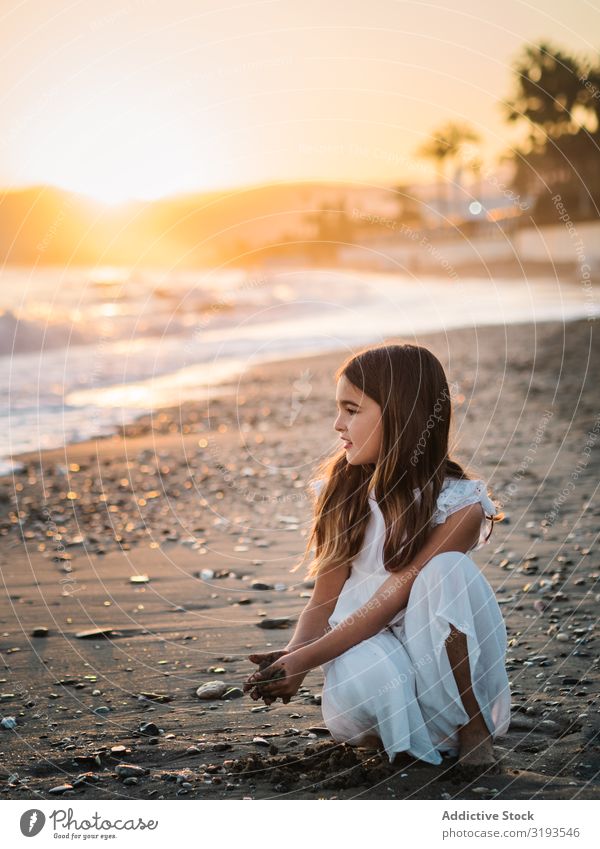 Adorable girl playing with sand on beach Girl Playing Sand Beach Delightful seaside Sunlight Cute Sunset Child Infancy Portrait photograph Pensive Dream Coast