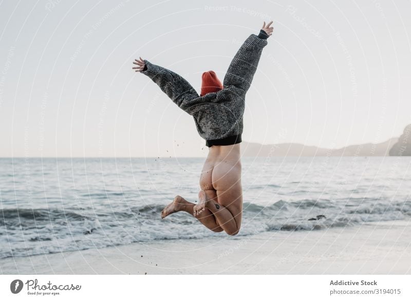 Unrecognizable woman enjoying freedom near waving sea Woman Jump Ocean Freedom Waves Bottom raised Hands up! Storm Nature Water Naked Sweater Hat Beach Coast