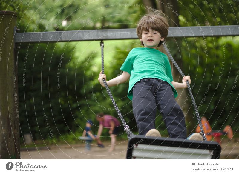 Child swinging on a playground Authentic naturally Boy (child) Summer fun Happy Joy Swing To swing Playing Infancy Playground swinging is like flying