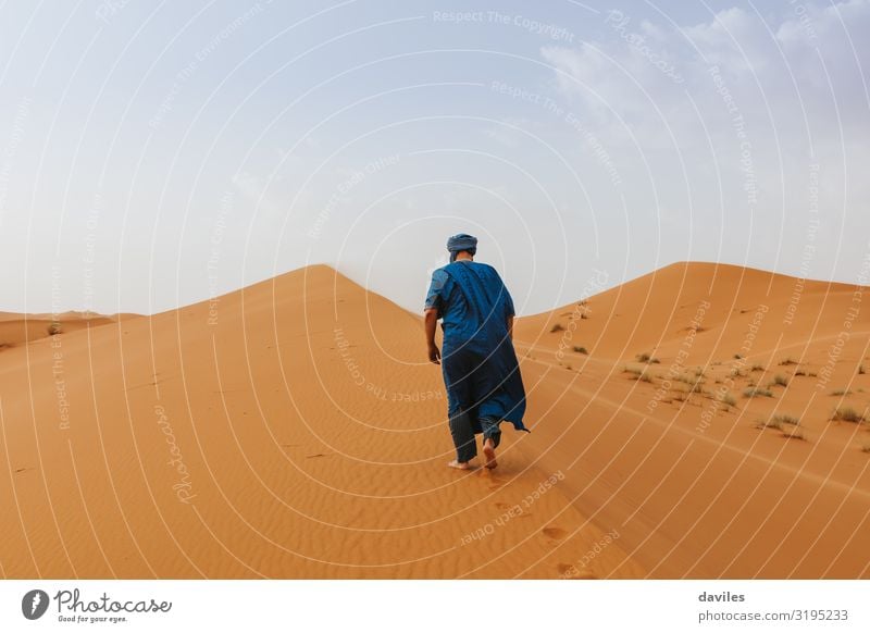 Arabian man in blue clothes walking on a desert dune. Lifestyle Elegant Style Exotic Vacation & Travel Tourism Trip Adventure Human being Man Adults 1