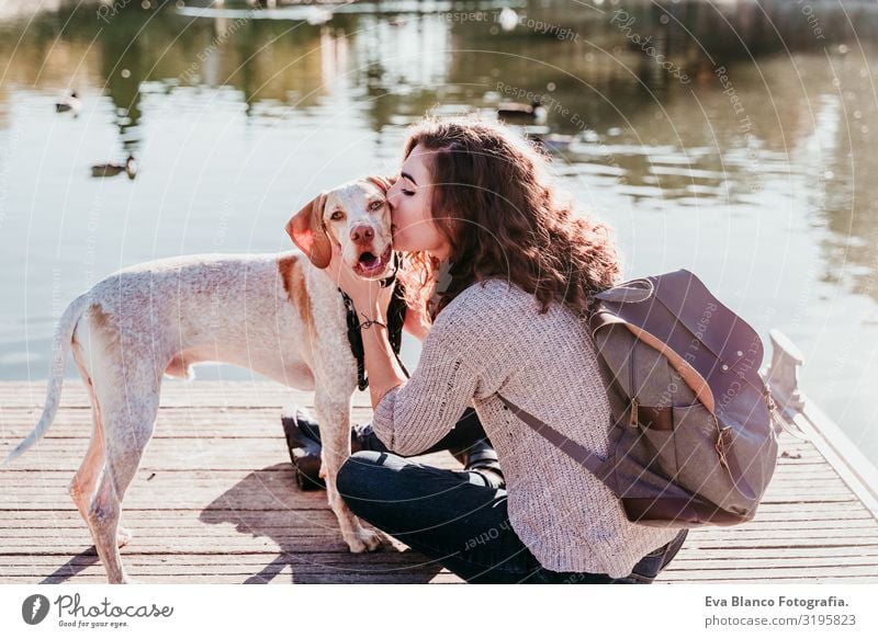young woman kissing her dog outdoors in a park with a lake. sunny day, autumn season Woman Dog Park Youth (Young adults) Exterior shot Love Pet owner Sunbeam