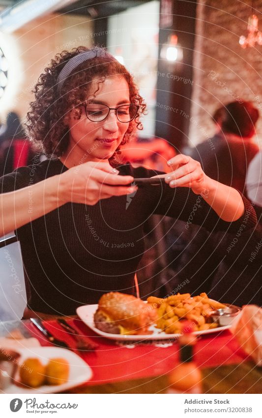 Young woman taking photo of food Woman Food Photography PDA Café burger French fries social media Lifestyle Leisure and hobbies Sit Table Technology device