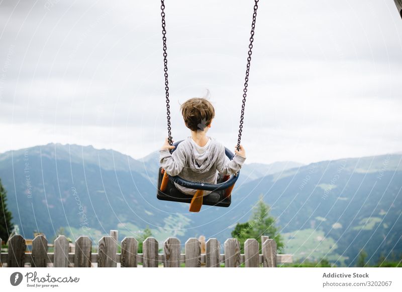 Child riding swings in cloudy day Flying Leisure and hobbies Cheerful Lifestyle Nature enjoyment Delightful amusement To swing Beautiful Sky Spinning Freedom