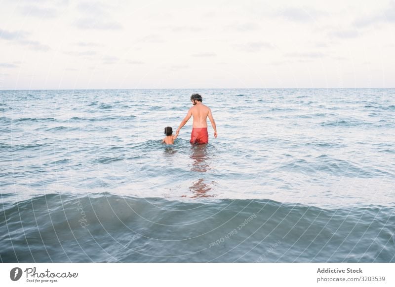Father with son walking in water Man Son Float in the water Coast Water Together holding hand Boy (child) Family & Relations Action Beach Vacation & Travel