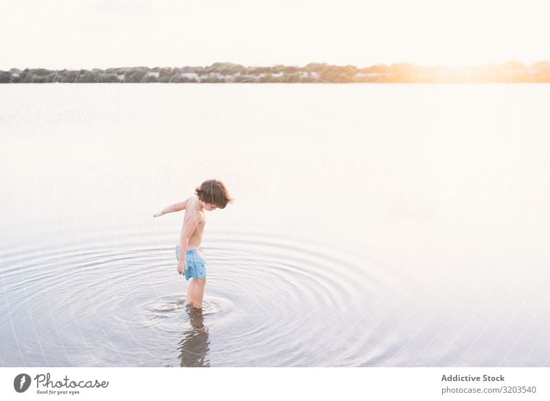 Boy walking in water of lake Boy (child) Beach Summer explore Water Walking Child Sunset Infancy Leisure and hobbies Vacation & Travel Bright Dream Loneliness