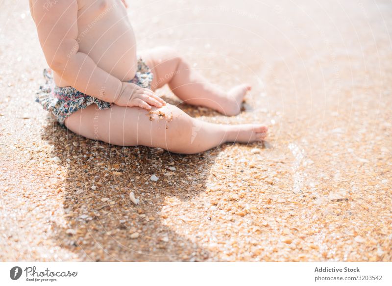 Crop view of anonymous cute baby sitting on beach Baby Beach Delightful Sand Wave Cute Summer Coast Leisure and hobbies Joy Child Vacation & Travel Strange Sun