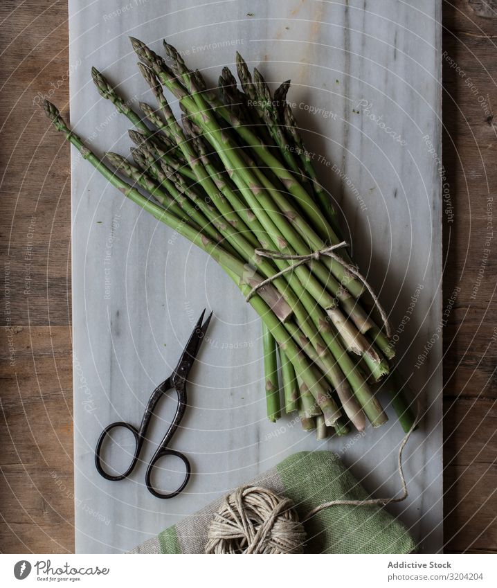 Arrangement of twine and asparagus on board Asparagus String Rustic Fresh Green Cooking Vegetable bunch Raw Healthy Nutrition Vegetarian diet Ingredients Diet