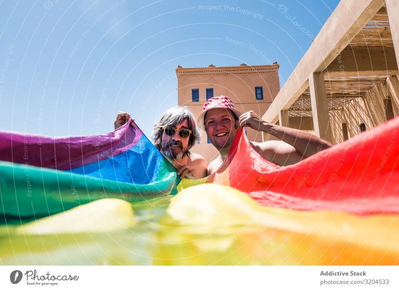 Happy gay couple in swimming pool Homosexual Couple Swimming pool lgbt Flag Overweight Together Love Resort Vacation & Travel Water Man hiding Cover Rainbow