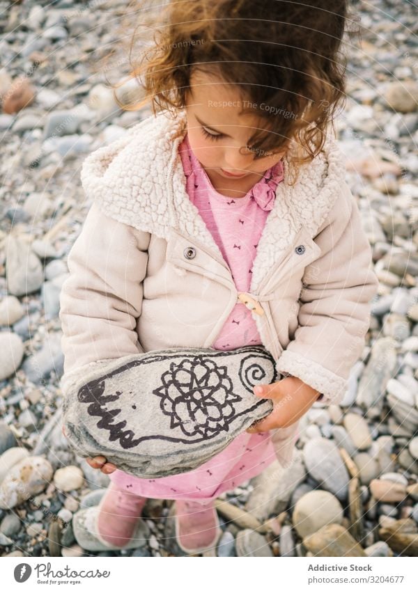 Girl holding painted stone while playing on beach Playing Stone Beach Painted Toddler Interest Cute Infancy seaside Intellect Creativity Serene Coast