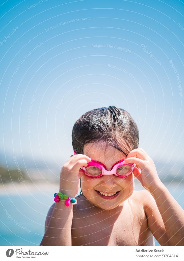 Cheerful girl in goggles after swimming in sea Girl Skiing goggles Ocean Cute Smiling Child taking off Blue sky Woman Summer Happy Leisure and hobbies
