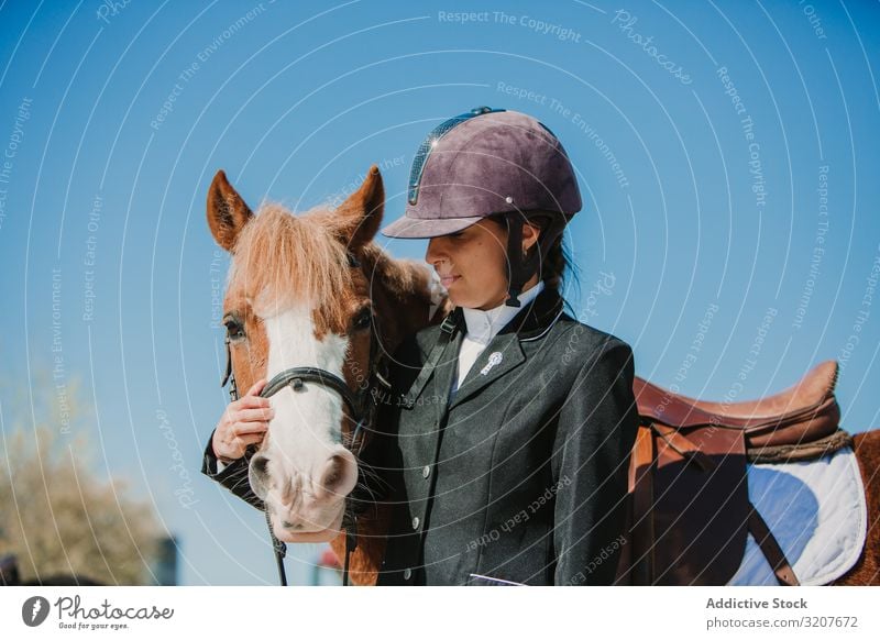 Woman in jockey outfit standing with horse woman stroke animal equestrian teen young pet friend love caress helmet touch beautiful mammal relationship stable