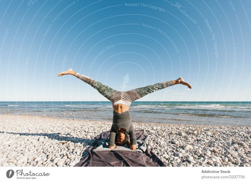 Beautiful woman practicing yoga on the beach at sunrise - a