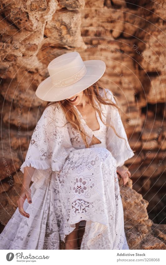 Gorgeous female sitting by ruined wall woman fashion stylish trendy glamorous model dress white lace clothes stone young person beautiful pretty attractive