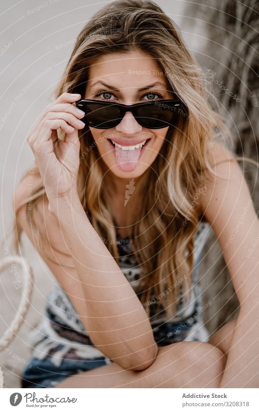 Portrait of young cheerful beautiful woman with sunglasses beach sticking out tongue fashionable funny glamorous grimace playful summer vacation travel