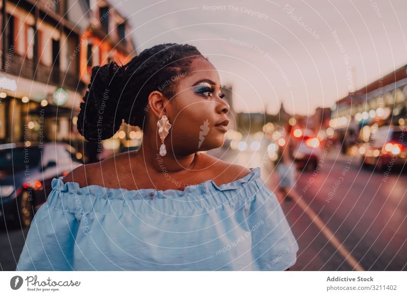 Content trendy African American woman on street content attractive stand vibrant sunset african american black ethnic city dress long hair curvy plump modern