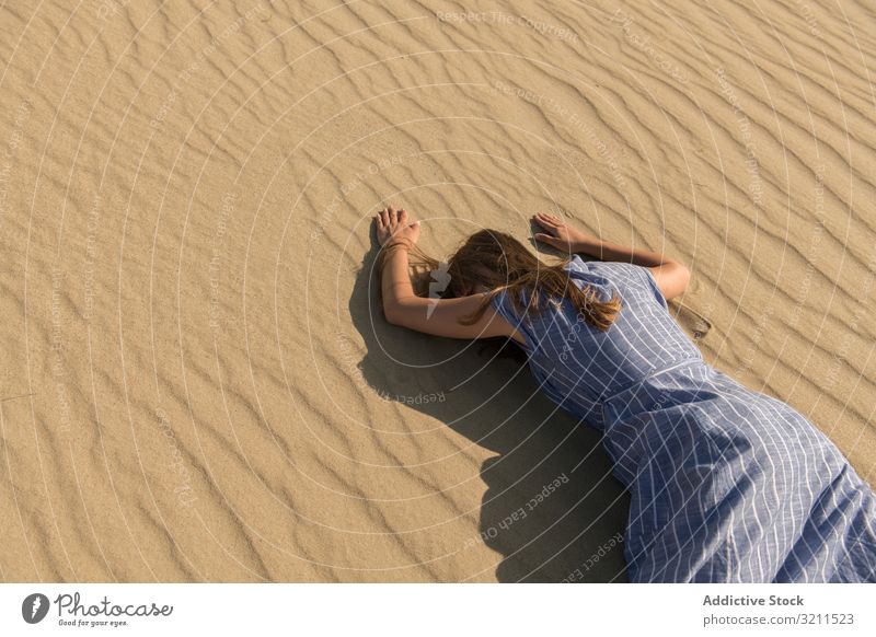 Young woman lying down on sand dune desert tired hot face down thirst exhausted sunlight casual drought summer dress freedom nida lithuania grass cloud