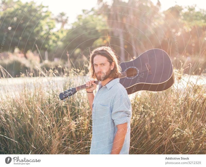 Hipster man in jungle with guitar hipster musician playing adventure trip summer lifestyle pensive male acoustic young entertainment leisure practice nature