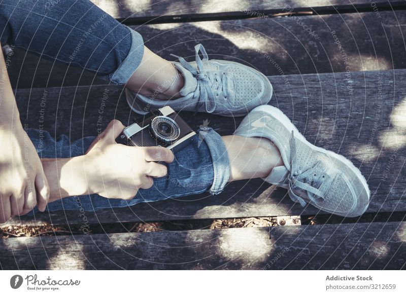 Woman sitting on bench with crossed legs camera woman blue sport trendy modern footwear photography stretching comfortable sneakers relaxation creative hipster