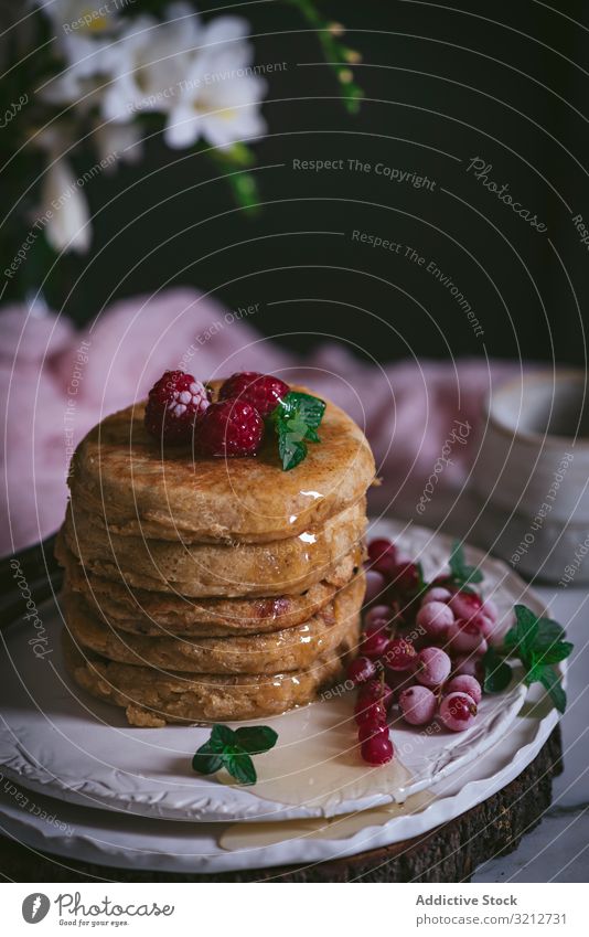 Pile of raspberry pancakes with honey on plate fresh pile golden brown stack marble porcelain tabletop flowers breakfast tasty utensil leaves stylish white