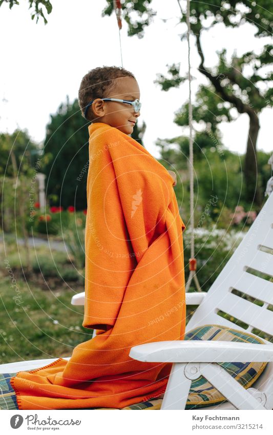 side view of colored boy covered with orange blanket smiling african american beautiful black black people carefree careless cheerful child childhood cute