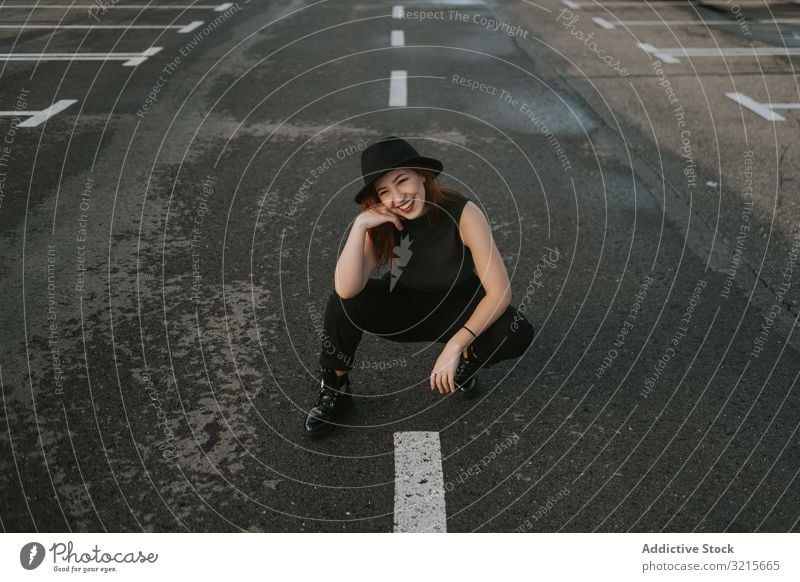 Smiling woman sitting on road with markings attractive empty markup stylish fashion young waiting happy direction model elegant lifestyle beautiful female