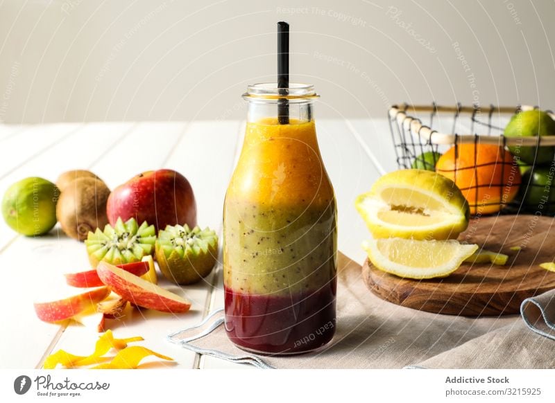 Bottle of layered smoothie fruit layers straw healthy table assorted mix sweet food diet fresh organic glass dessert kiwi apple lemon lime beverage nutrition
