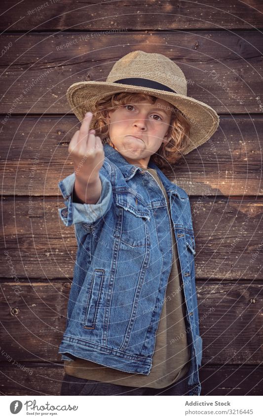 Cheeky self confident boy gesturing fuck you standing kid little middle finger obscene showing fun casual summer funny child active freedom hand adorable