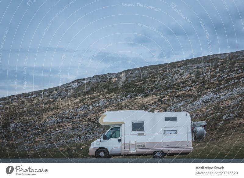 Camper near hill on cloudy day camper travel countryside slope sky road weather vehicle parked auto transport trailer caravan adventure trip journey tourism