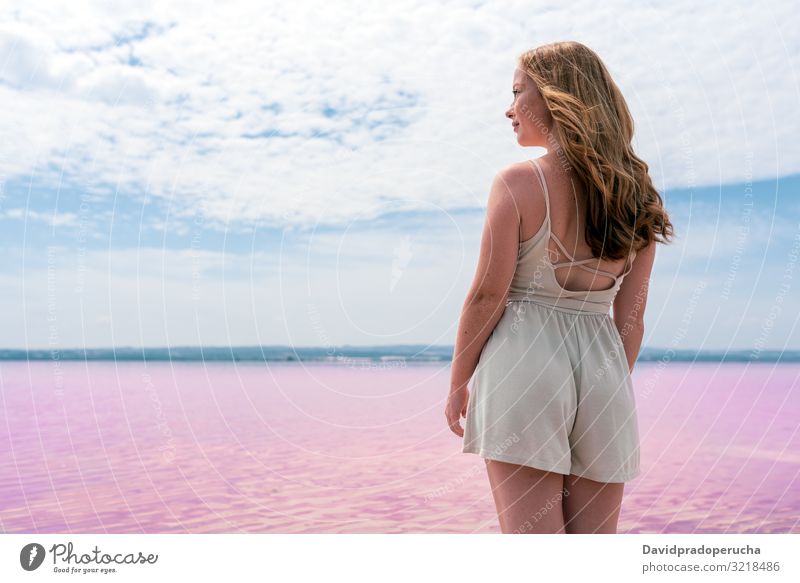 Back view of cute teenager woman wearing summer clothes on pink lake Alicante Spain beach beautiful blue sky coast coloration colorful cool copy space dress