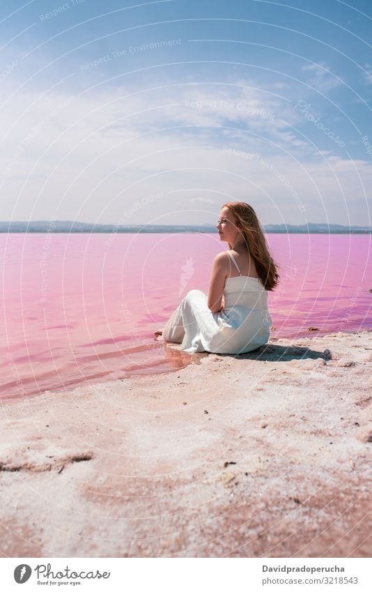 cute teenager woman wearing white dress sitting on an amazing pink lake young saline romantic tourism summer freckles happy alone sea colorful water copy space