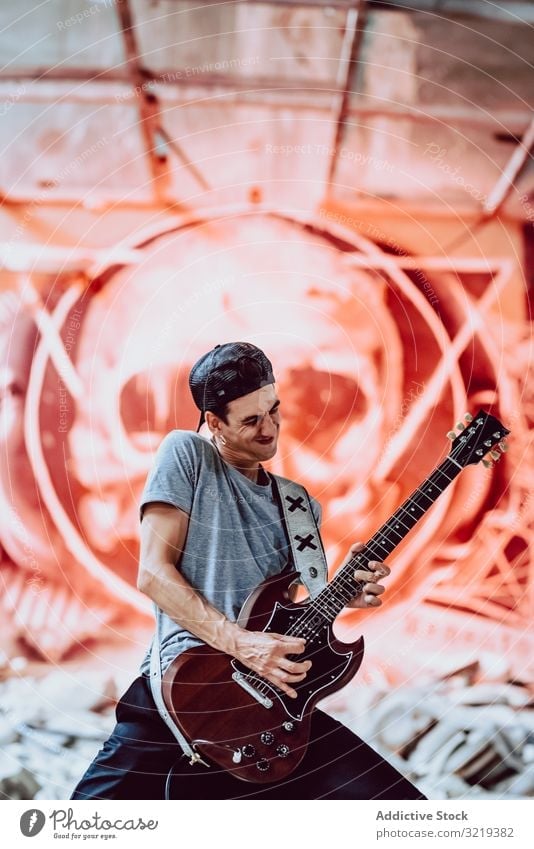 Musician playing electric guitar man musician grunge rebel metal instrument entertainment abandoned graffiti skull male lifestyle performer heavy sound rock