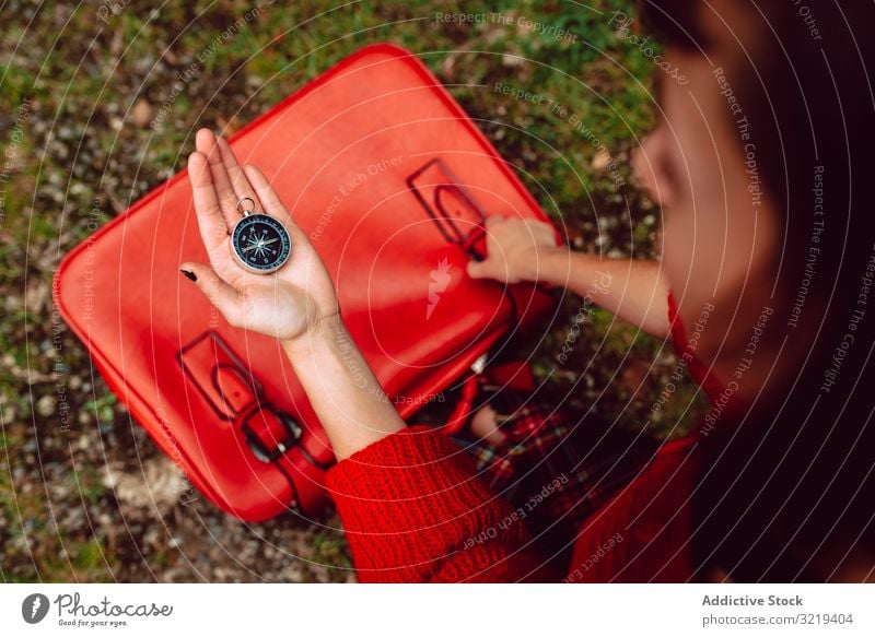 Woman with red suitcase on ground checking compass destination orienteering baggage packing woman vacation travel young holiday location navigation journey