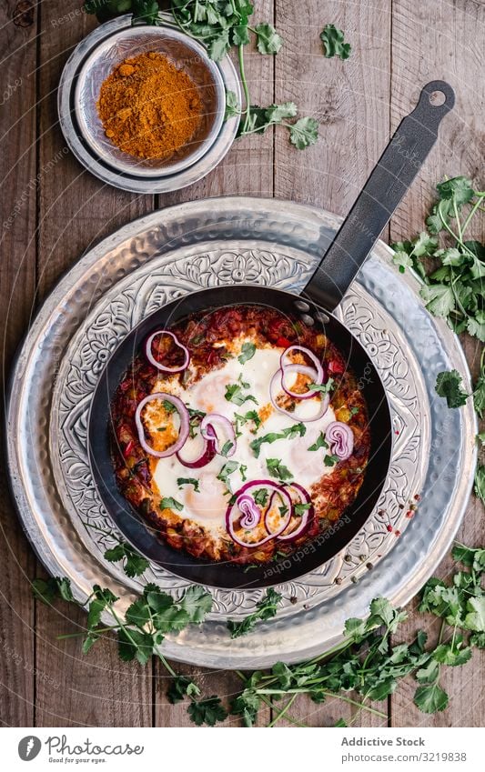 Fragrant shakshuka with onion rings in pan cuisine traditional turmeric food green meal vegetable bowl recipe wooden cooking gourmet dish tasty spicy red