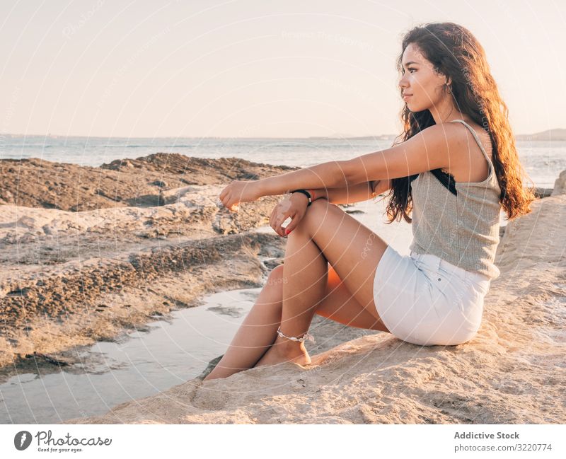Pretty trendy young ethnic woman on beach at sunset modern casual pretty content sunlight adult coastline brunette attractive sandy stylish hipster summer