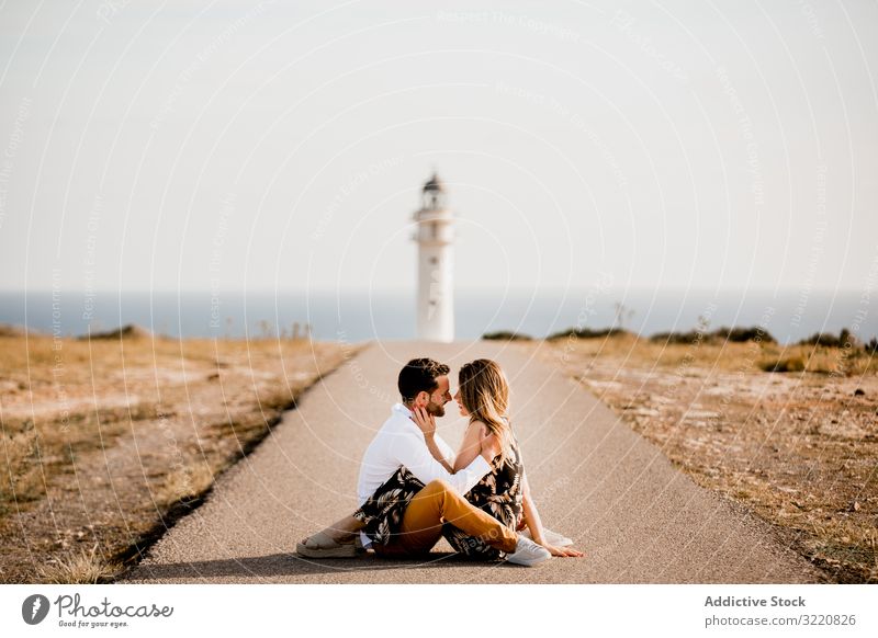 Smiling lovers cuddling on path to sea Formentera balearic islands Spain couple summer cuddle seashore road smile tender lighthouse asphalt freedom success