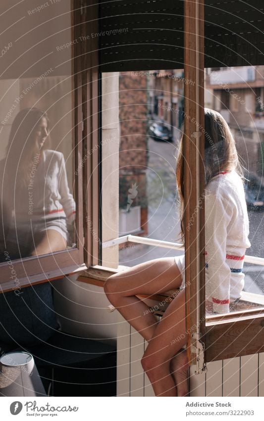 Woman sitting on window sill woman pensive tender thoughtful home calm sensual attractive female apartment casual young beautiful pretty upset morning relax