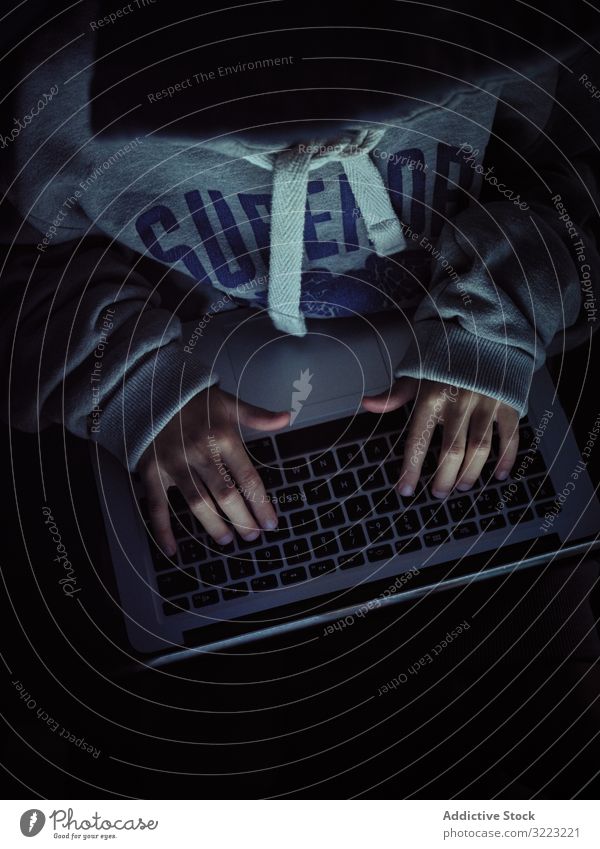 Anonymous hacker typing on laptop keyboard code boy database little using computer programmer virus digital password software kid child device gadget browsing