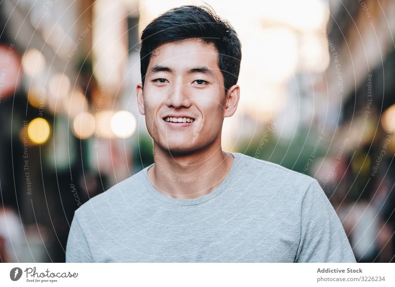 Confident Asian man walking along city street confident content casual t shirt handsome urban stroll modern summer asian ethnic young adult town relaxed