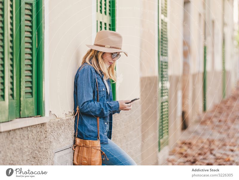 Woman with smartphone leaning on stone house woman happy beautiful talking attractive charming relaxation street female confident model communication thoughtful