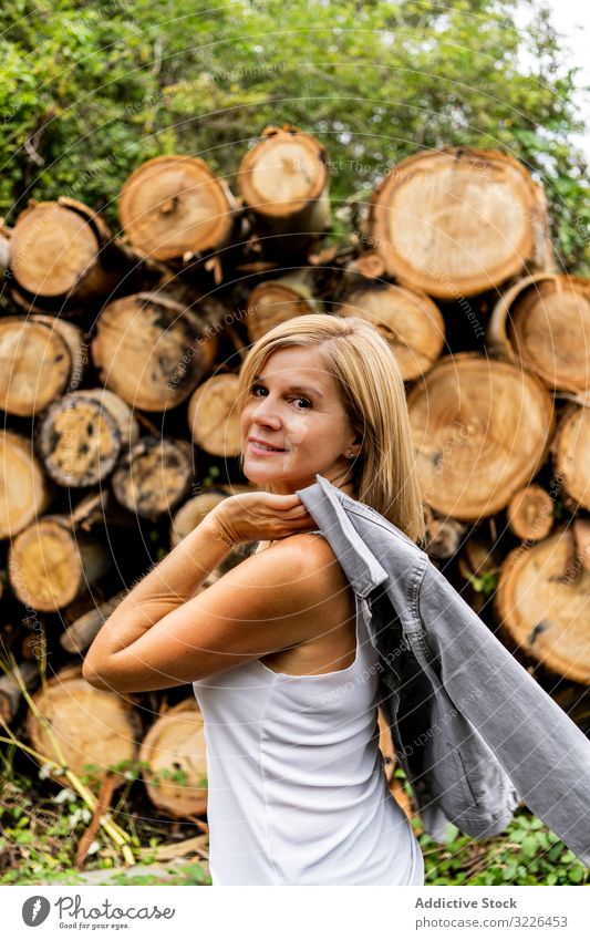Woman taking off jacket on background of woodpile in forest log walking trunk woman firewood face model nature holiday smiling vacation weather lady journey